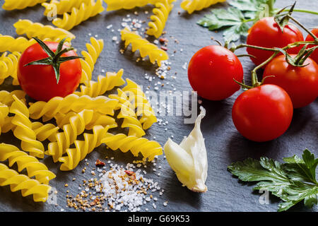 Ingrédients pâtes fusilli (noir) sur fond d'ardoise. Banque D'Images