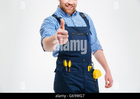 Portrait of a smiling male builder showing thumb up isolé sur fond blanc Banque D'Images