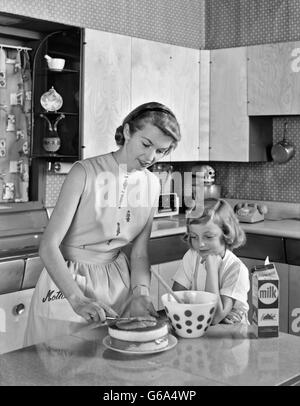 1950 Mère et fille EN GLAÇAGE GÂTEAU CUISINE DOUBLE COUCHE Banque D'Images