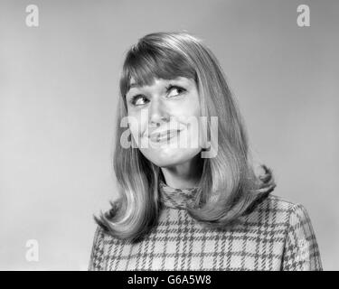 1960 Femme avec de longs cheveux STYLE FLIP AVEC BANGS À LA RECHERCHE AVEC L'EXPRESSION DU VISAGE sourire amusé Banque D'Images