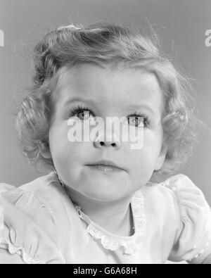 1950 SMILING LITTLE GIRL PORTRAIT TODDLER LOOKING UP AT CAMERA Banque D'Images