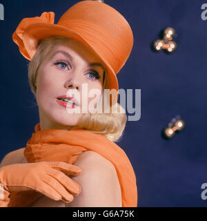 À la mode des années 1960, blonde aux yeux bleu femme mannequin portant un chapeau orange avec foulard ASSORTIS ET DES GANTS Banque D'Images