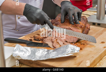 Coupe en tranches minces en chef pastrami boeuf closeup on cutting board Banque D'Images