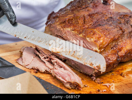 Coupe en tranches minces en chef pastrami boeuf closeup on cutting board Banque D'Images