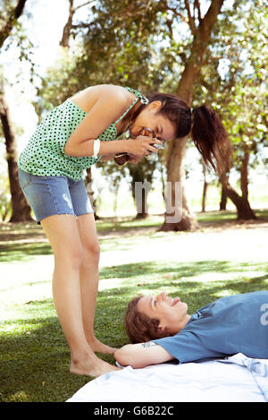 Young woman photographing boyfriend at park Banque D'Images