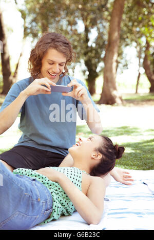 Young man photographing copine avec smartphone Banque D'Images