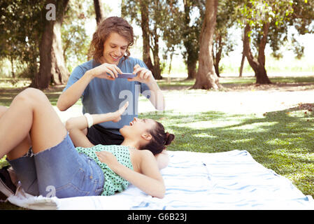 Young man photographing copine avec smartphone Banque D'Images