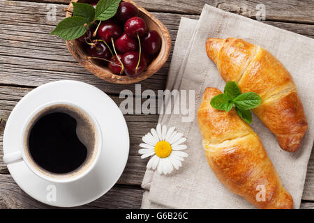 Des croissants, du café tasse et cerises sur table en bois. Vue d'en haut. Concept de petit-déjeuner Banque D'Images