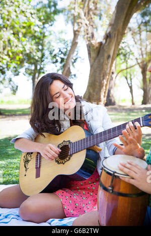 Woman playing guitar in park Banque D'Images