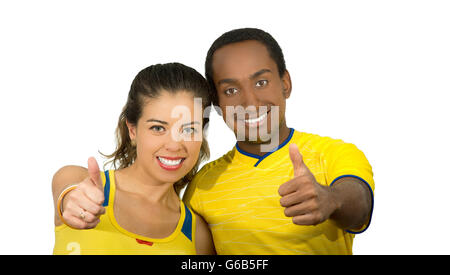 Charmant couple interracial portant des maillots de football jaune giving Thumbs up à l'appareil photo, l'arrière-plan blanc studio Banque D'Images