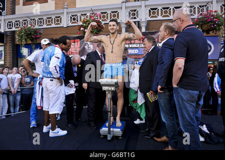 Le champion du monde du poids léger à fort grammage de WBO Nathan fléchit intelligemment ses muscles sur la balance pendant la pesée à Queen Street, Cardiff. Banque D'Images