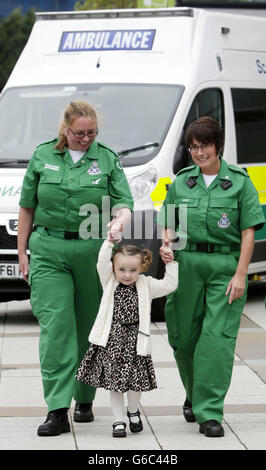 Casey McLean, âgée de trois ans, avec June Maxwell (à gauche) et Julie Grainger (à droite), deux des ambulanciers paramédicaux qui lui ont sauvé la vie après son arrêt cardio-respiratoire à Glasgow. Banque D'Images