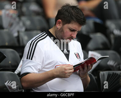 Football - Barclays Premier League - Fulham / Arsenal - Craven Cottage.Un fan de Fulham portant le nouveau maillot adidas domicile lit le programme d'allumette dans les tribunes Banque D'Images