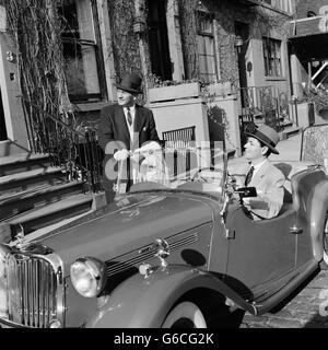 Années 1950 Années 1960 DEUX BUSINESSMEN TALKING SUR STREET one sitting in convertible deux places de voiture de sport anglais Banque D'Images