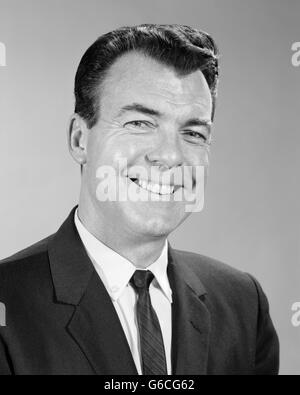 1960 SMILING BUSINESS MAN PORTRAIT PORTANT CRAVATE COSTUME LOOKING AT CAMERA Banque D'Images