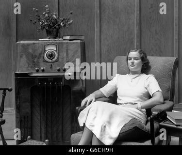 Années 1930 Années 1940 SERIOUS WOMAN SITTING IN Living Room à l'ÉCOUTE DE LA RADIO Banque D'Images