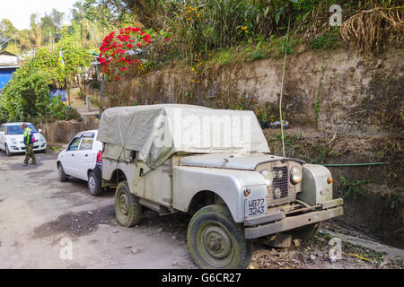 Les vieux Land Rover Series II classique couché voiture partiellement couvert sur la route à Darjeeling Banque D'Images