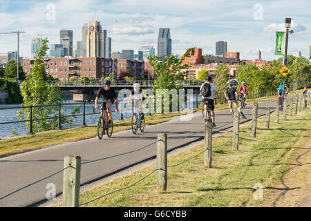 Les gens la bicyclette sur la piste cyclable du Canal de Lachine à Montréal, avec en arrière-plan et la tour du marché Atwater Banque D'Images