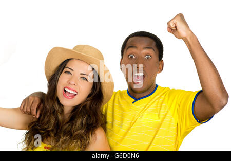 Charmant couple interracial portant des maillots de football jaune joyeusement à acclamer, blanc fond studio Banque D'Images