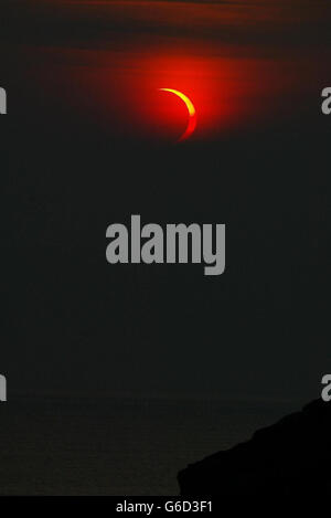 La couverture nuageuse se déplace pendant un moment pour afficher la lune passant devant le soleil à la fin de sa phase sur les sommets de la falaise près de Durness dans Sutherland, au nord de l'Écosse. *... Une éclipse annulaire est similaire à une éclipse totale, mais le diamètre apparent de la lune n'est pas assez grand pour couvrir le disque du soleil, laissant un anneau fin de lumière visible du soleil. La raison en est que l'orbite de la lune est elliptique. Si une éclipse se produit quand la lune est près de son point le plus éloigné de la Terre (apogée) alors elle ne couvre pas complètement le soleil. Banque D'Images