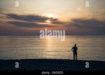 Jeune homme est à la recherche au lever du soleil. Banque D'Images