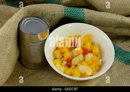 Cocktail de fruits en conserve dans un bol avec pouvez sur de la toile de jute Banque D'Images