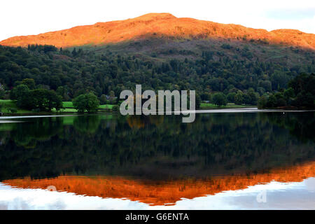 Le soleil d'automne illumine les sommets près du lac Grasmere dans le district des lacs, Cumbria. Banque D'Images