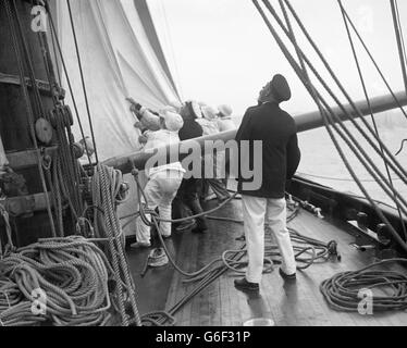 Le roi George V observe la grande voile qui est hissé à bord du Britannia, lors d'une course de yacht à Cowes. Banque D'Images