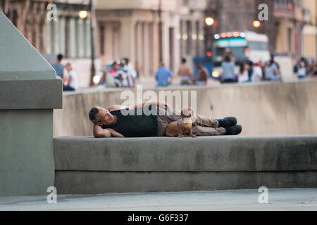 L'homme ayant une sieste sur le mur en face de la mer Le Malecon (route du littoral) à La Havane, Cuba Banque D'Images