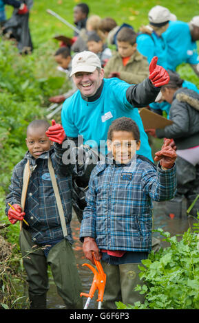 : les volontaires Jaden et Adam de l'école primaire de Haseltine à Sydenham avec Sean Wooden Directeur principal, soutien de la performance de la marque, DoubleTree de Hilton, participent à l'événement DoubleTree de Hilton pour le programme de la semaine mondiale de service de Hilton à Ladywell Fields à Catford South London, Aider à nettoyer une partie de la Tamise. Banque D'Images