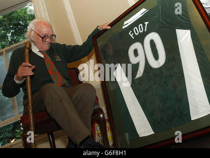 L'ancien chef du Parti travailliste Michael foot regarde un maillot de football qui lui a été remis en cadeau au gay Hussar de Soho, à Londres, lors d'une fête organisée pour marquer son 90e anniversaire. Banque D'Images