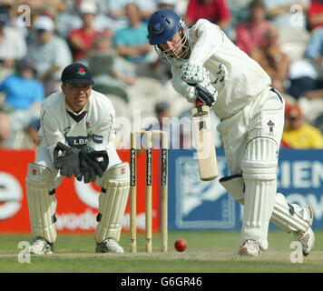 Le batteur du Sussex Muray Goodwin dirige une livraison de Gary Keedy du Lancashire, alors que Warren Hogg regarde pendant le match de championnat du comté de Frizzell à Old Trafford, Manchester. Banque D'Images