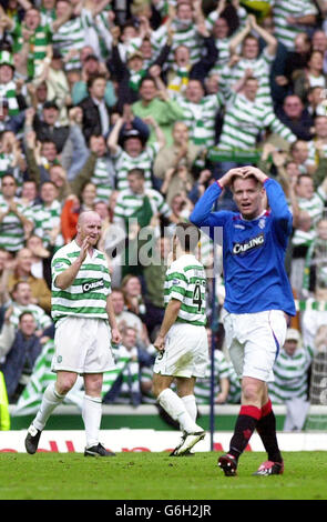 John Hartson (à gauche) du Celtic célèbre avec son coéquipier Liam Miller au coup d'envoi à plein temps, alors que Michael ball (au premier plan) des Rangers tient sa tête en déjection après leur match de la Bank of Scotland Premier League au stade Ibrox, à Glasgow. Celtic a gagné 1-0. Banque D'Images