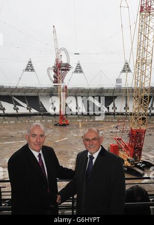 Kim Bromley-Derry, chef de la direction du Conseil de Newham (à gauche), serre la main avec Dennis Hone, chef de la direction de London Legacy Development Corporation, alors que des grues de levage lourdes sont inutilisées au stade Queen Elizabeth Olympic Park, à Stratford-est de Londres, après que les conditions météorologiques ont retardé le retrait des premiers panneaux de projecteurs,Alors que le travail commence au transformer en un lieu polyvalent tout au long de l'année et la résidence permanente du West Ham United football Club et du nouveau stade de compétition national pour UK Athletics. Banque D'Images