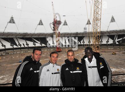 (De gauche à droite) West Ham United Players , le capitaine d'équipe Kevin Nolan, Mark Noble, Joe Cole et Mohammed Diame, se tiennent sur la terrasse du stade Queen Elizabeth Olympic Park, à Stratford est de Londres, Comme les grues de levage lourdes s'assoient au repos après que les conditions météorologiques ont retardé le retrait des premiers panneaux de projecteurs, alors que les travaux commencent au transformer en un lieu multi-usage tout au long de l'année et la résidence permanente du West Ham United football Club et du nouveau stade de compétition national pour UK Athletics. Banque D'Images