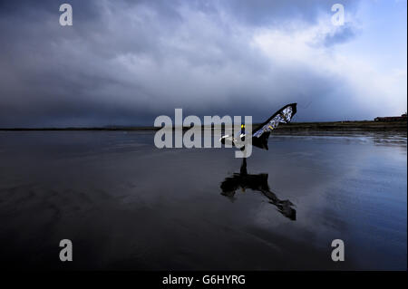 Un surfeur cerf-volant marche sur la plage dans des vents forts et un temps de tempête spectaculaire avec son cerf-volant attaché à son dos à Rest Bay, Porthcawl, pays de Galles. Banque D'Images