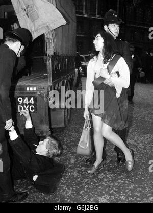 Une jeune fille portant une ceinture noire est à moitié soulevée vers un camion alors que d'autres policiers ont des difficultés avec un homme qui, toujours avec une cigarette entre ses lèvres, résiste passivement à la suite d'une manifestation à Trafalgar Square, à Londres, contre la visite royale grecque. Des membres du Comité des 100 et des partisans de la Ligue pour la démocratie en Grèce se sont réunis sur la place. La police a empêché une marche prévue à Buckingham Palace, où le roi Paul et la reine Frederika séjournaient. Il y a eu un certain nombre d'arrestations. Banque D'Images