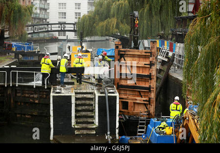 Une équipe de travailleurs de la construction, employée par le Canal and River Trust, aide à guider le remplacement des portes d'écluses en position à l'écluse de Hampstead Road, autrement connu sous le nom de Camden Lock, à Camden, dans le nord de Londres. Banque D'Images