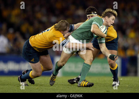 Brian O'Driscoll d'Irlande traverse les kitles de l'Australie Bill Young (à gauche) et Al Baxter dans leur défaite de 16-15 par l'Australie dans la piscine UN match de la coupe du monde de rugby 2003 au Telstra Dome, Melbourne, Banque D'Images