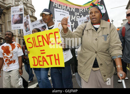 Calitas Motola, 56 ans (à gauche), qui a été torturé sous le régime du président Mugabe pour avoir soutenu un parti d'opposition, se joint à la coalition End the Silence, un groupe de protestation contre les violations des droits de l'homme au Zimbabwe, alors qu'ils marchent vers Whitehall, Londres. Banque D'Images