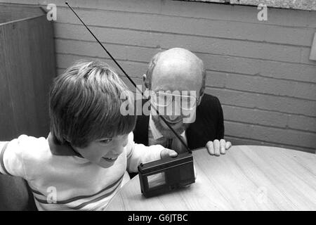 Sir Clive Sinclair, fondateur et président de Sinclair Research, regarde Joe Challands, 8 ans, en appréciant d'être le premier propriétaire d'un téléviseur de poche Sinclair de 2 pouces. Banque D'Images