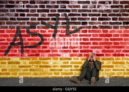 Demandeur d'asile assis en face d'un mur avec l'écriture de l'asile et de drapeau allemand, la tête dans ses mains, Computer Graphic Banque D'Images