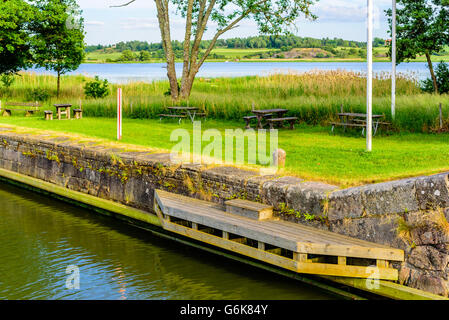 Place d'amarrage dans un canal avec un pont en bois ou jetty et une borne de granit dans l'herbe à côté de la voie navigable. Gota canal à Mem Banque D'Images