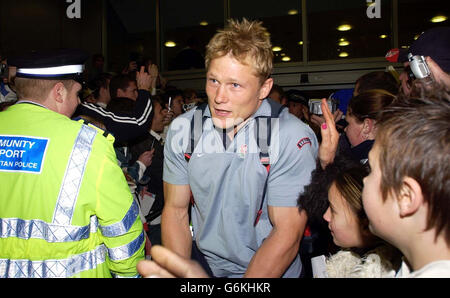 Le joueur de rugby d'Angleterre Josh Lewsey est escorté à travers la foule à l'aéroport de Londres Heathrow , tandis que l'équipe est revenue d'Australie avec la coupe du monde. Des milliers de fans se sont réunis pour accueillir à la maison l'équipe qui a remporté le trophée après avoir battu l'Australie en plus de temps samedi. Banque D'Images