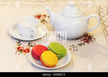 Macarons colorés français sur une assiette, tasse et théière, selective focus Banque D'Images
