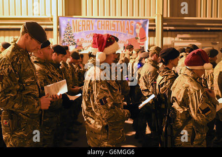 Des soldats se rassemblent à l'hôpital de campagne du Camp Bastion, en Afghanistan, pour un service de chants de noël dirigé par le chœur médical de la Force interarmées du Royaume-Uni, avec de la musique de la bande de l'Artillerie royale. Banque D'Images