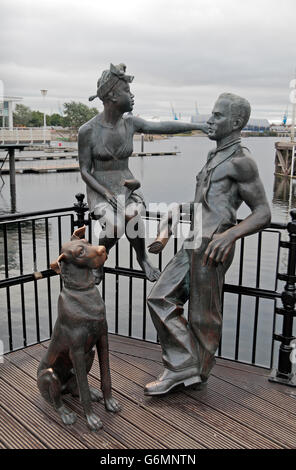 "Des gens comme nous", un groupe de statues d'un homme, femme et chien par John Clinch, Mermaid Quay, la baie de Cardiff, Glamorgan, Pays de Galles. Banque D'Images