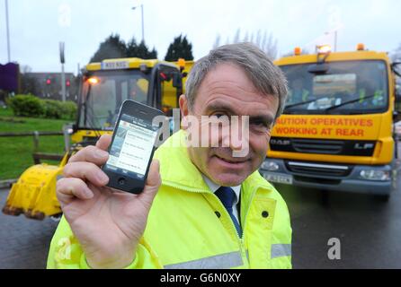 Le ministre des routes Robert Goodwill essaie la nouvelle application pour smartphone « Fill This Hole », qui permet à un plus grand nombre de cyclistes de signaler des problèmes de pothole, lors de sa visite à Chadderton Way, Oldham. Banque D'Images