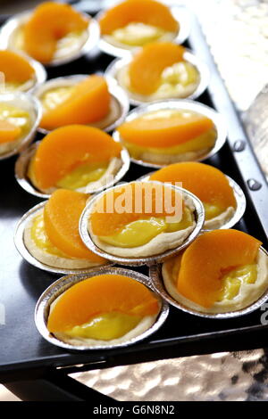 Close up of Peach tartelettes en noir plateau de service Banque D'Images