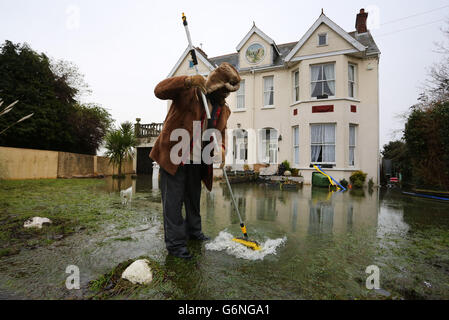 Kye Gbangbola élimine les eaux d'inondation de l'extérieur de sa maison près du pont Chertsey à Chertsey, Surrey, car des communautés le long de la Tamise dans tout le Surrey, le Berkshire et l'Oxfordshire ont été prévenus qu'elles risquent d'être inondées. Banque D'Images